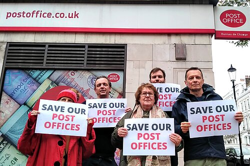 Lib Dem Activists outside kensington post office, holding a "Save our Post Offices" Sign