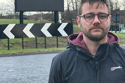 Stephen O'Brien standing in front of a giant TV advertising screen on Hastings Hill roundabout, Sunderland