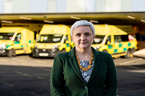 Alex Brewer MP standing in front of ambulances