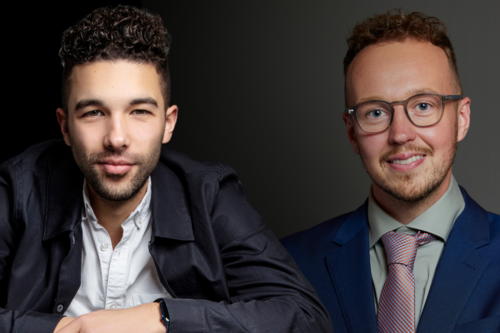 Pablo O'Hana and Adam Dance MP side by side against a dark, gradient background. Pablo is on the left wearing a dark jacket over a white shirt, resting his arms on a surface. Adam is on the right wearing a blue suit, pale green shirt, and patterned tie, smiling directly at the camera.