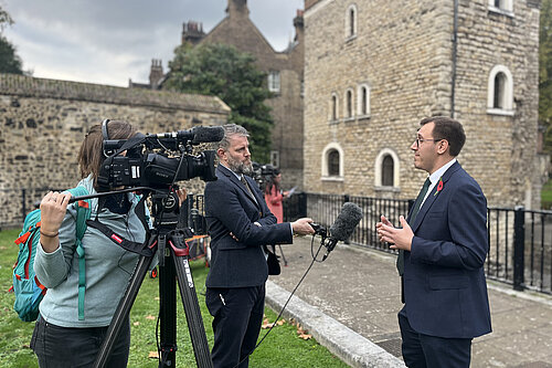 Tom Gordon stood speaking to the media on College Green near Parliament