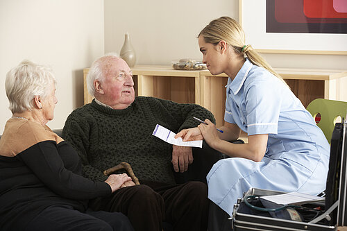 A nurse treating two old people.