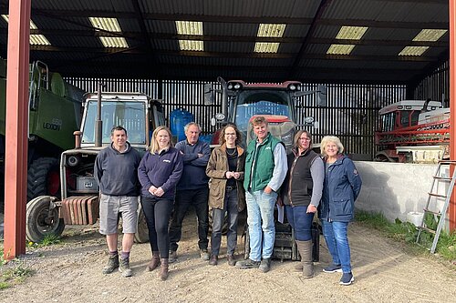 Alison Bennett MP with local farmers in a barn infront of tractors