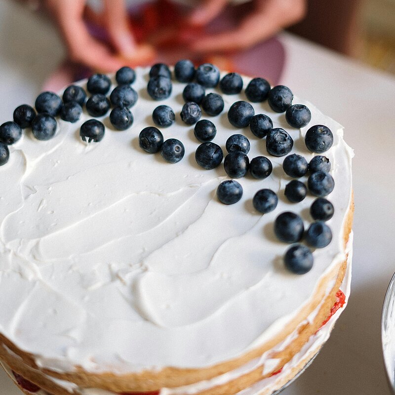 Someone placing berries on a cake