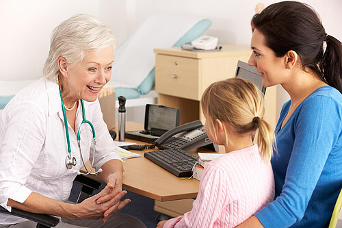 A mother holding a child whilst speaking to a GP