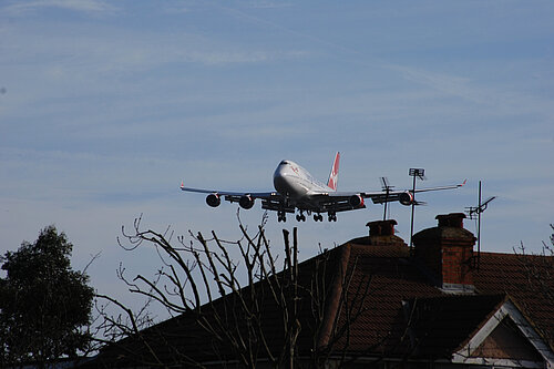 A plane flying close to houses.
