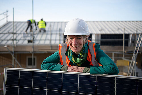 Pippa Heylings at a construction site with hard hat and solar panel