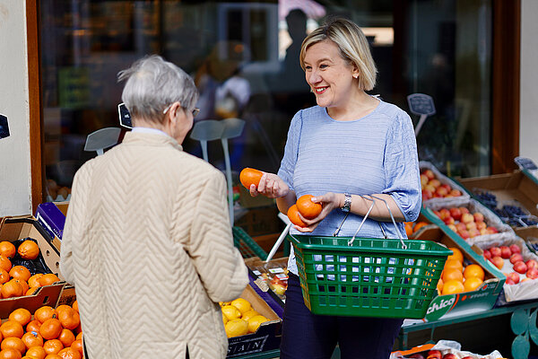 Lisa speaking with a resident outside a fruit and veg shop