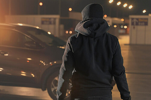 A hooded man holding a knife.