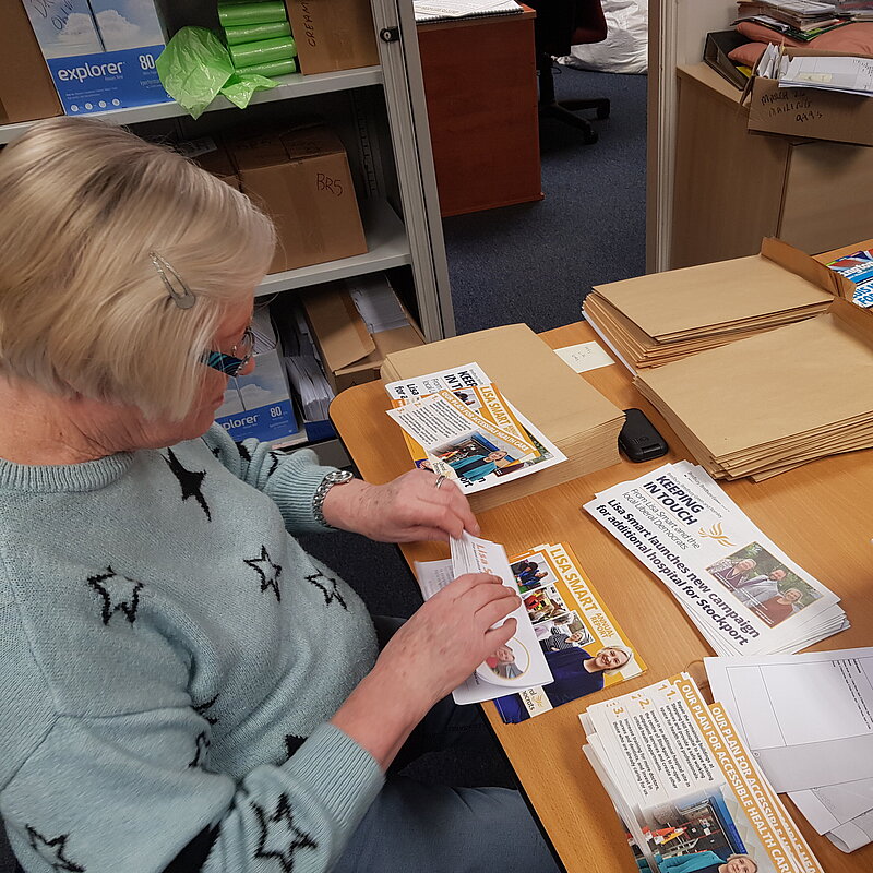 Person sat at a table stuffing envelopes