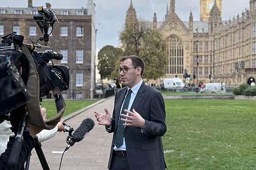 Tom Gordon stood speaking to the media outside the Houses of Parliament
