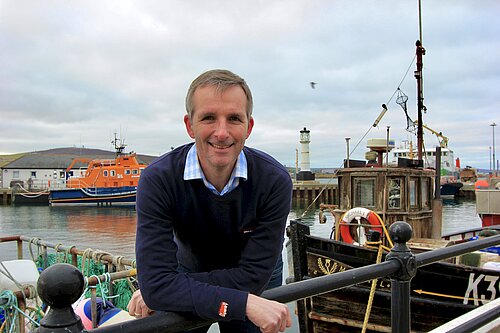 Liam McArthur pictured in front of boats. 