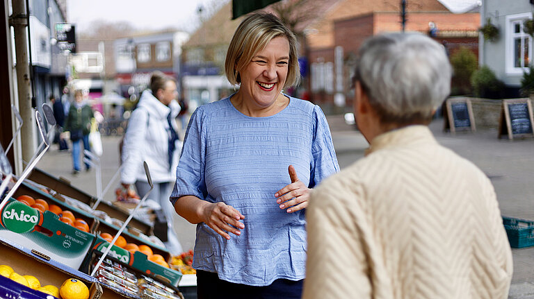 Lisa speaking with resident outside fruit and veg stall