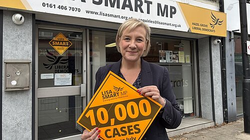 Lisa Smart MP outside her Romiley Constituency Office with a “10,000 cases” Lib Dem Diamond