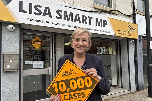 Lisa Smart MP outside her Romiley Constituency Office with a “10,000 cases” Lib Dem Diamond