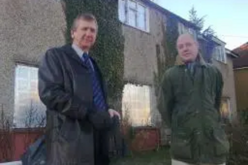 Cllrs. Graham Pooley & Ashley Final standing in front of the boarded up house