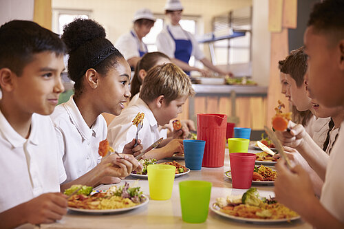 Four children eating food from a plate.