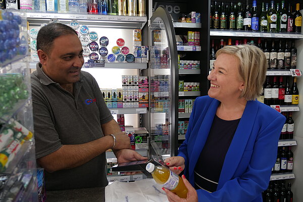 Lisa buying a drink while speaking with store owner Jack