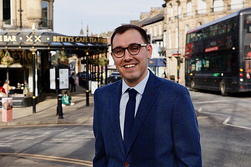 Tom Gordon stood in front of Bettys and a 36 bus in Harrogate