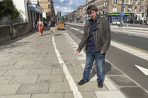 Councillor Jack Caldwell pointing at a line painted on the pavement