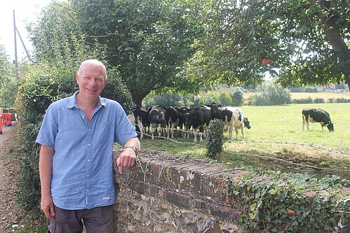 Cllr Mike Sole standing in front of a field of Cows 