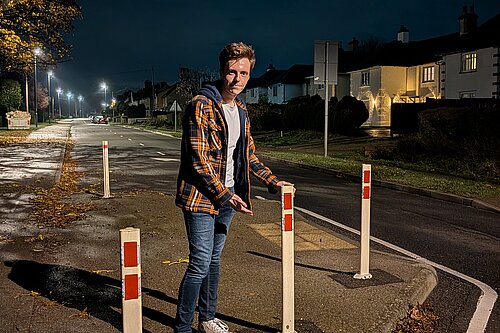 Cllr Nathan Hunt standing by traffic calming bollards, with new red reflectors