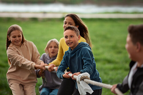 Photo of kids playing tug-of-war in the park