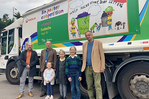 6 People standing in front of a waste vehicle.