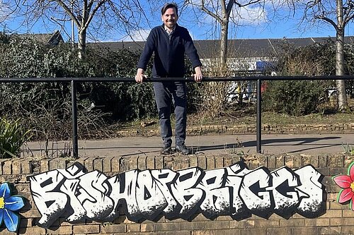 Adam Harley leaning against a metal railing over a wall with graffiti art reading Bishopbriggs