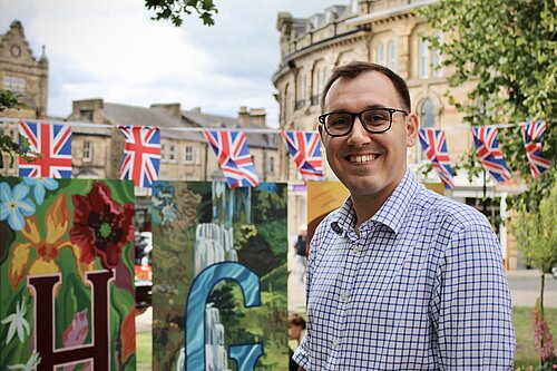 Tom Gordon MP stood in Central Harrogate with Union Jack Flags behind him
