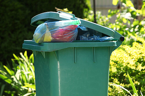 A wheelie bin overflowing with rubbish.