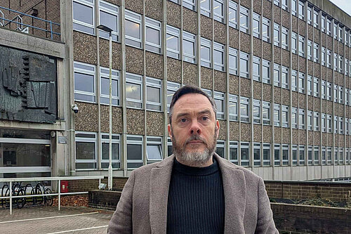 Councillor Kevin West standing in front of County Hall's four storeys of rather brutalist office windows