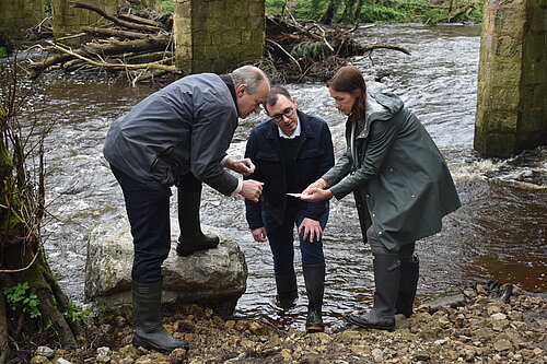 Tom Gordon, Ed Davey and Cllr Hannah Gostlow stood testing water in the River Nidd for pollutants and E Coli