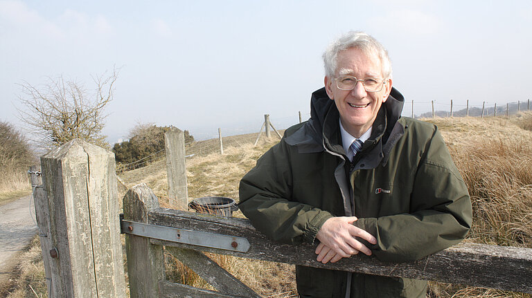 Andrew leaning on a fence.