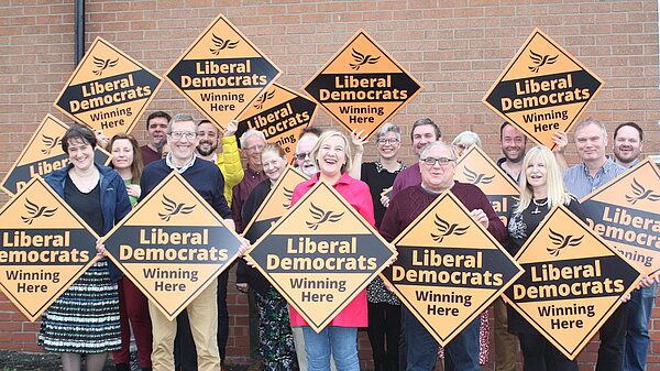 A group of Liberal Democrats supporters with diamond shaped party signs