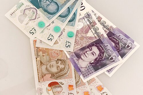 Seven pound coins on top of a ten pound note.