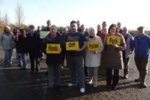 Group of Protestors in Preston Park holding Hands Off Preston Park placards